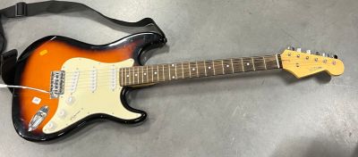 les guitares sont posées par terre dans une pièce, avec une sangle autour du manche