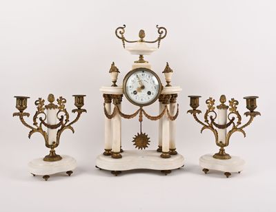 trois bougies et une horloge posées sur une table