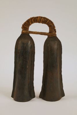 une paire de clochettes noires entourées d'une corde, posées sur une surface blanche