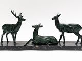three bronze statues of deer on a marble base