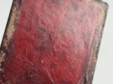 a hand holding a book with a red cover on it