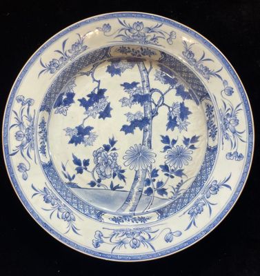 a blue and white plate with a bird and flowers on it
