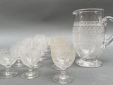 five glasses and a pitcher sitting on a table