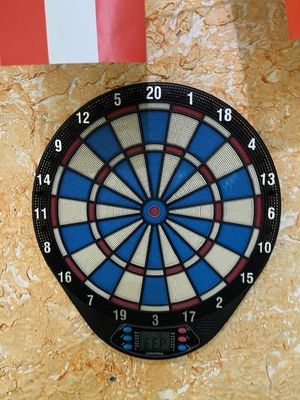 une fléchette accrochée au mur, sur laquelle est représentée une horloge