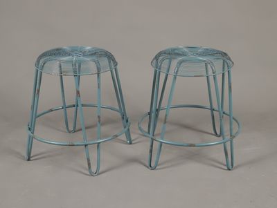 une paire de tabourets en métal bleus avec des pieds en métal, sur fond gris