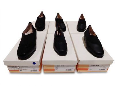 quatre paires de chaussures noires posées sur des cartons, sur une surface blanche