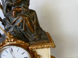 une statue d'un homme assis au sommet d'une horloge