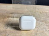 des AirPods de la marque Apple posés sur une table en bois, à côté d'une boîte transparente