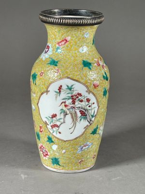 vase jaune orné de fleurs et d'oiseaux peints sur un fond gris