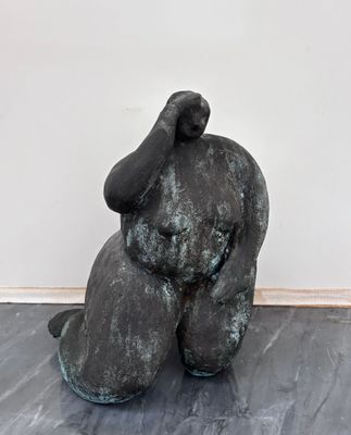 une statue représentant un homme assis sur un plancher en bois