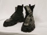 une paire de bottes militaires noires à lacets sur fond blanc