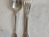 deux cuillères en argent et une fourchette posées sur une nappe blanche