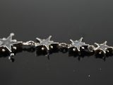 silver star earrings on a black surface with reflection