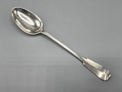 cuillère en argent à long manche posée sur une surface grise