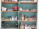 de nombreux plats et tasses sur les étagères de la cuisine