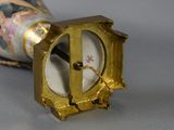 a gold clock sitting on top of a vase