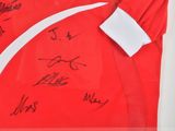 a framed picture of a red shirt with autographs on it