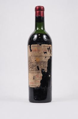 une vieille bouteille de vin posée sur une surface blanche