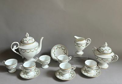 un service à thé blanc et doré posé sur une table