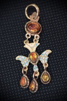 a close up of a silver and gold pendant with a bird on it
