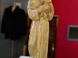 statue d'une femme tenant un enfant dans ses bras, posée sur un socle dans une pièce