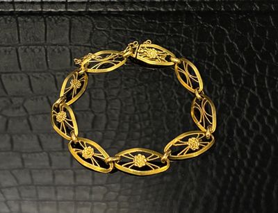 gros plan d'un bracelet en or sur une surface en cuir noir