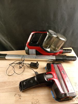 un aspirateur rouge et noir posé sur une table en bois