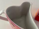 a heart shaped bowl with a handle on a table