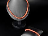 un collier de perles orange et un oreiller noir sur fond noir