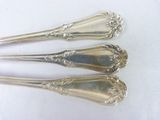 three silver spoons sitting on top of each other on a table