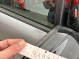 a person that is holding a measuring tape in front of a car