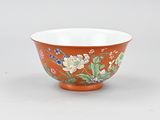 an orange and white bowl with flowers and leaves on it