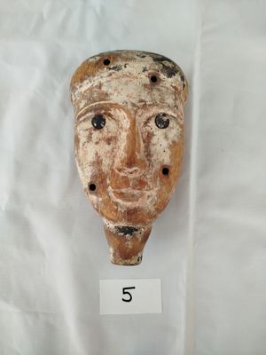 une image représentant un masque en argile posé sur un drap blanc