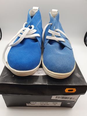 des baskets bleues et blanches avec des lacets blancs, posées sur une boîte