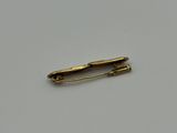 a close up of a gold pin on a white surface