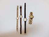 trois montres et un bracelet sont posés sur une surface blanche