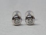 une paire de boucles d'oreilles en diamant posées sur une surface blanche