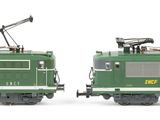 two green trains sitting side by side on a white surface