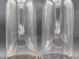 two clear glass cloches with wooden bases on a grey background