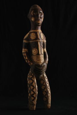 une statue en bois représentant un homme debout devant un fond noir