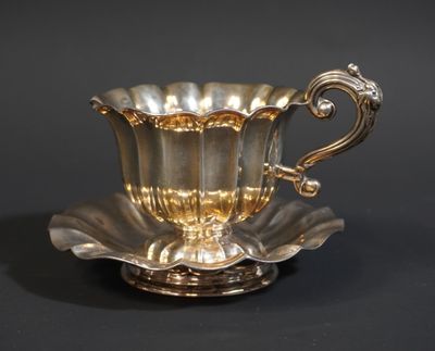 une tasse et une soucoupe anciennes en argent sur fond noir