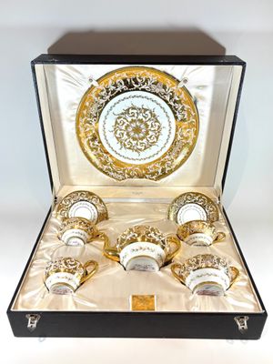 a gold and white cup and saucer set in a box