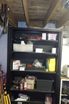une bibliothèque noire remplie d'objets divers dans un garage