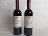 two bottles of red wine sitting next to each other on a white surface