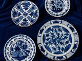 quatre assiettes bleues et blanches ornées de motifs floraux, posées sur une nappe bleue