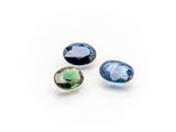 three blue and green tourmaline gems on a white background