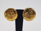 a pair of gold earrings on a black stand