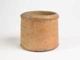 un petit vase brun posé sur une surface blanche