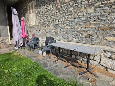 tables and chairs outside of a stone building with umbrellas in the background