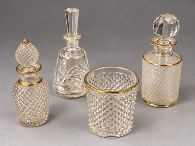 three glass bottles and a glass cup on a table